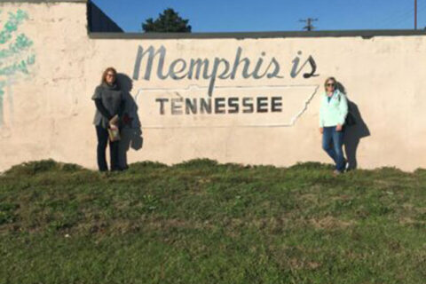 Two women standing beside the wall