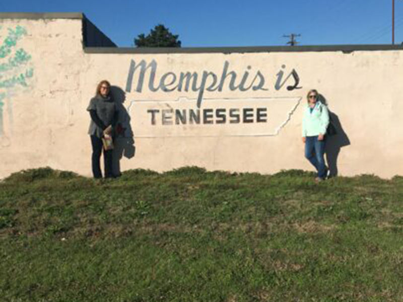 Two women standing beside the wall